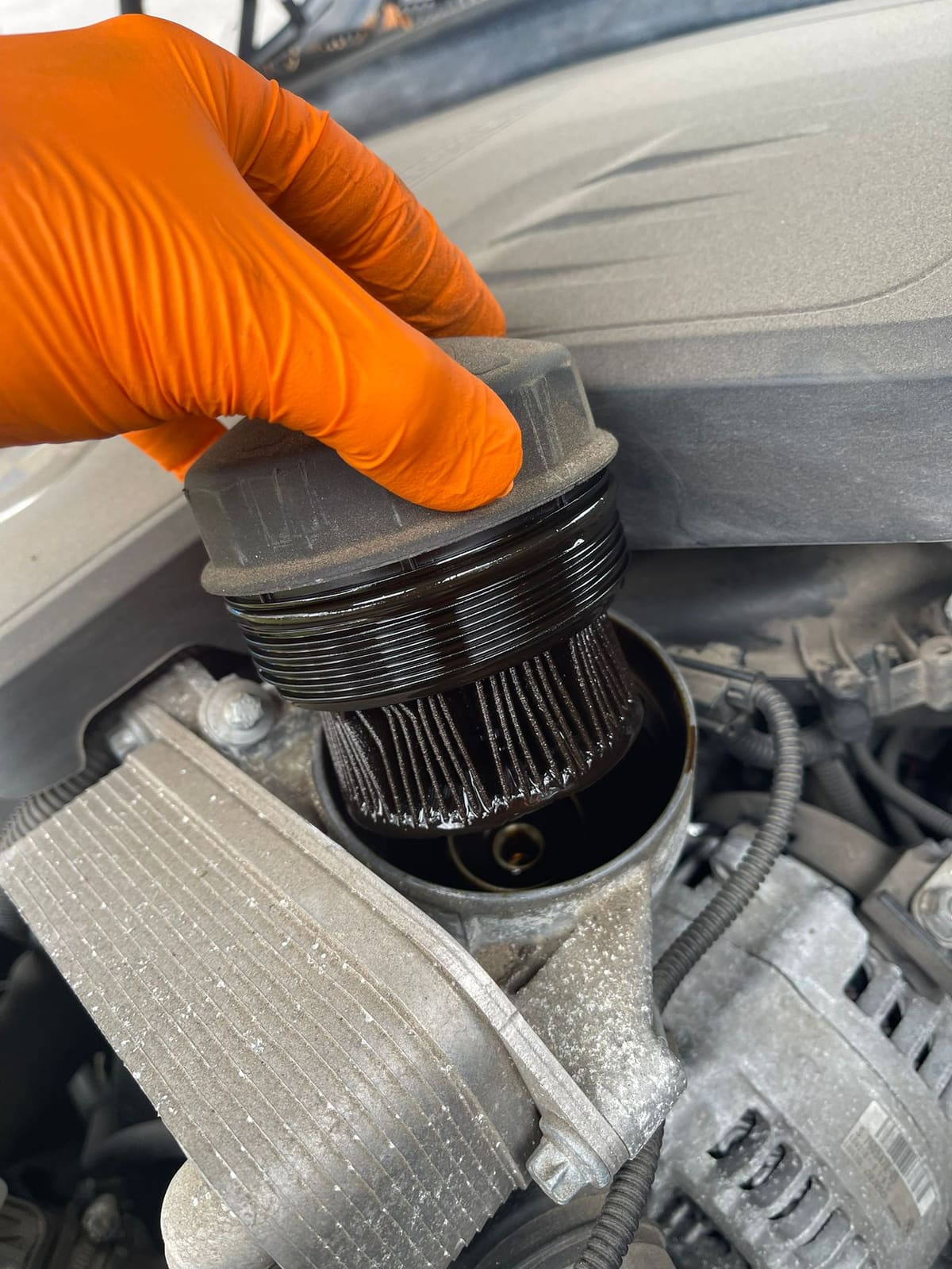 Used oil filter being lifted out of an engine during a mobile car service